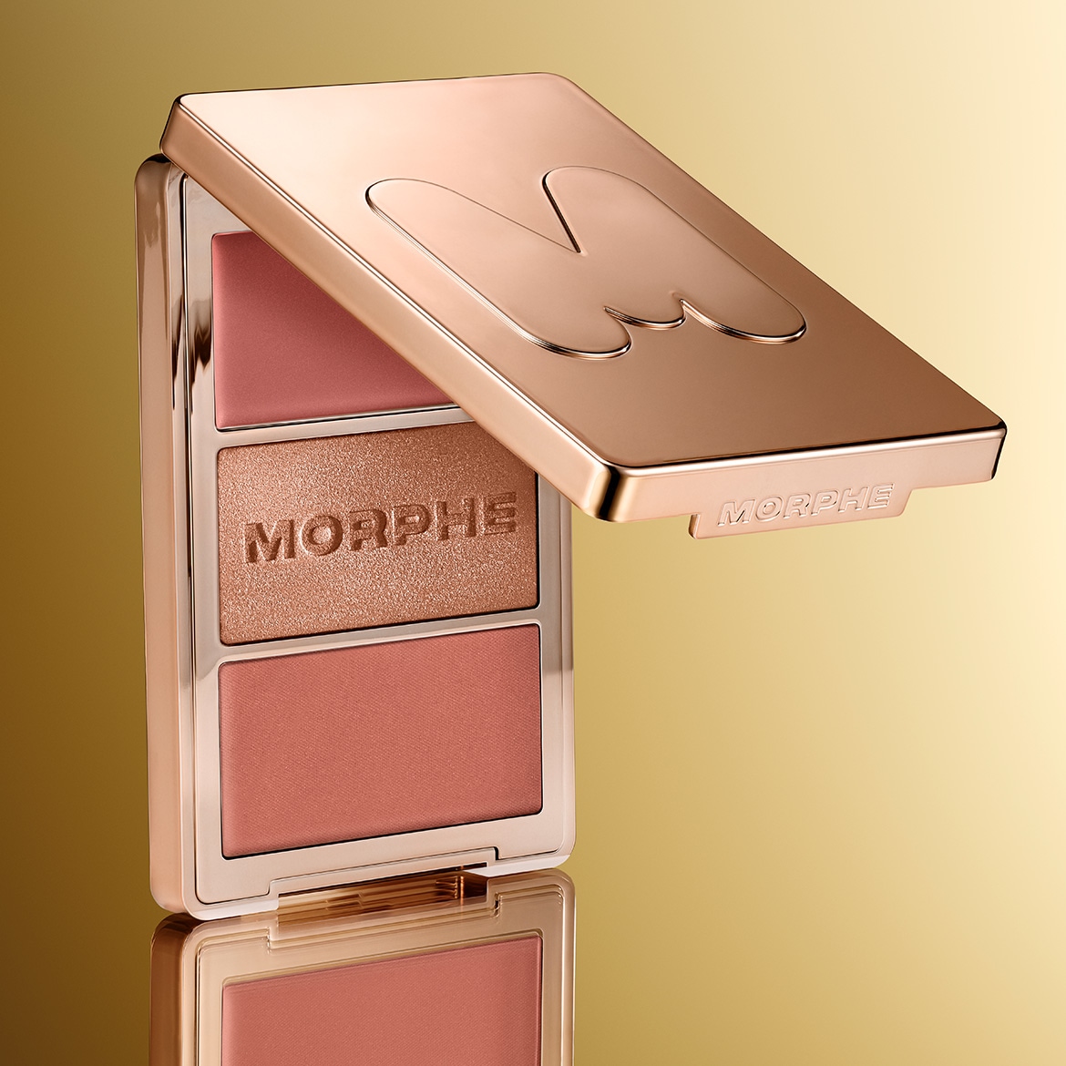 Auksinė „Morphe“ makiažo paletė su atidarytu dangteliu, atskleidžiančiu skaistalus ir bronzantą, skirtą veido spalvai paryškinti.