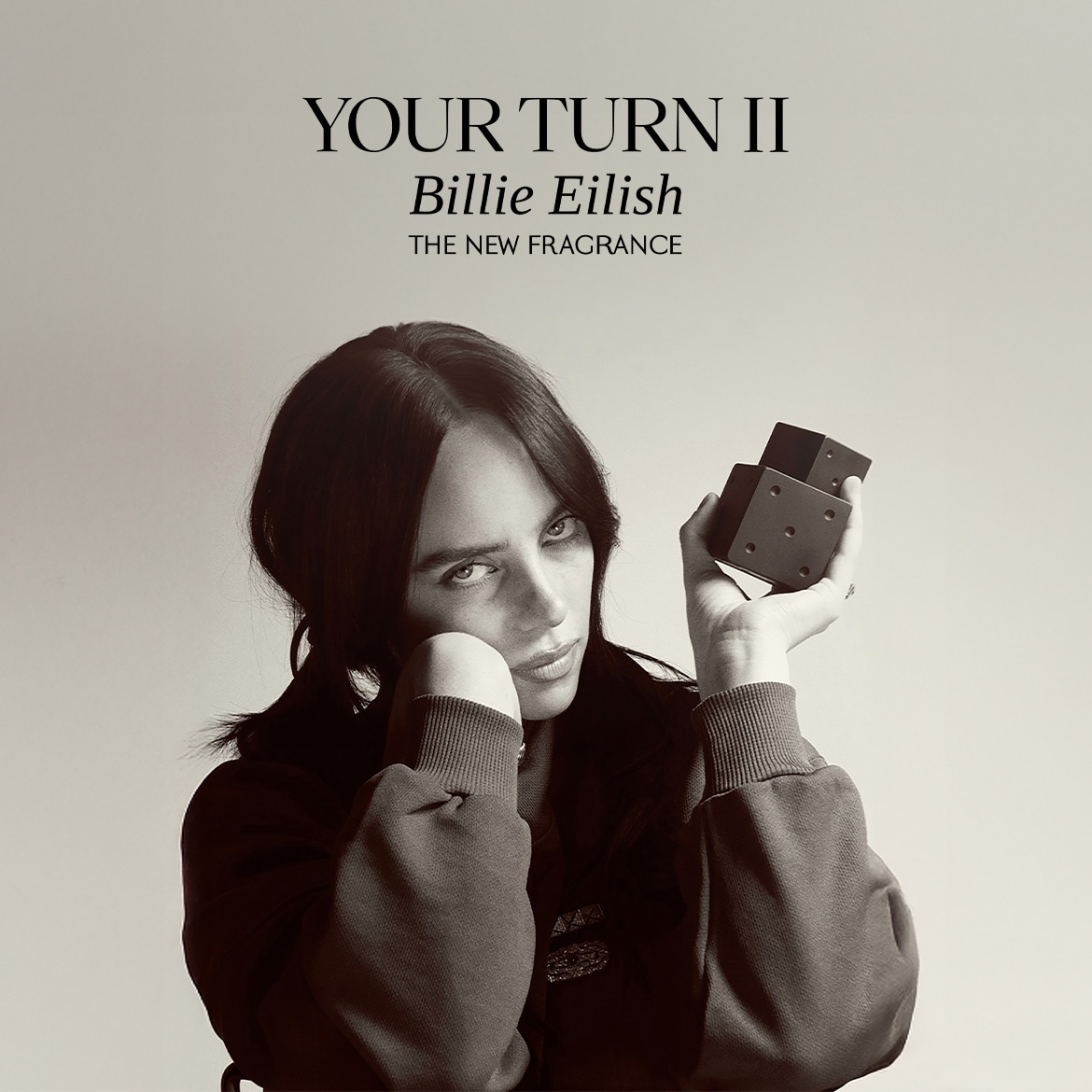 Reklama su tekstu „Your Turn II Billie Eilish – The New Fragrance“, centre – asmuo laiko kvepalų buteliuką prie veido.