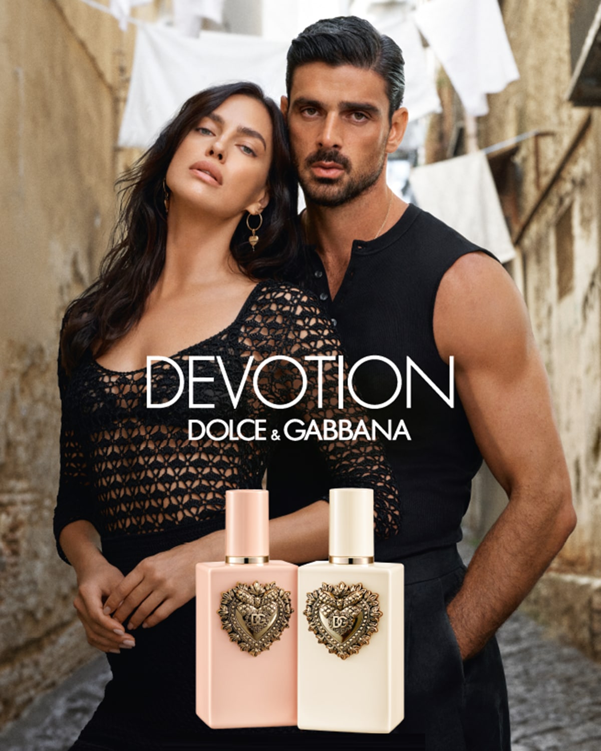 Atraskite „Dolce & Gabbana Devotion“ kvepalus, kuriuos reklamuoja Irina Shayk ir Michele Morrone, įkūnijantys aistrą ir eleganciją su dviem švelniais rausvos ir kreminės spalvos buteliukais, papuoštais auksine širdimi.
