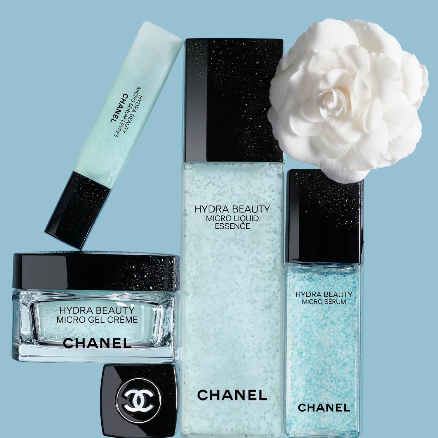 Keli CHANEL Hydra Beauty produktai – kremas, serumas ir esencija – su kamelijos žiedu mėlyname fone.