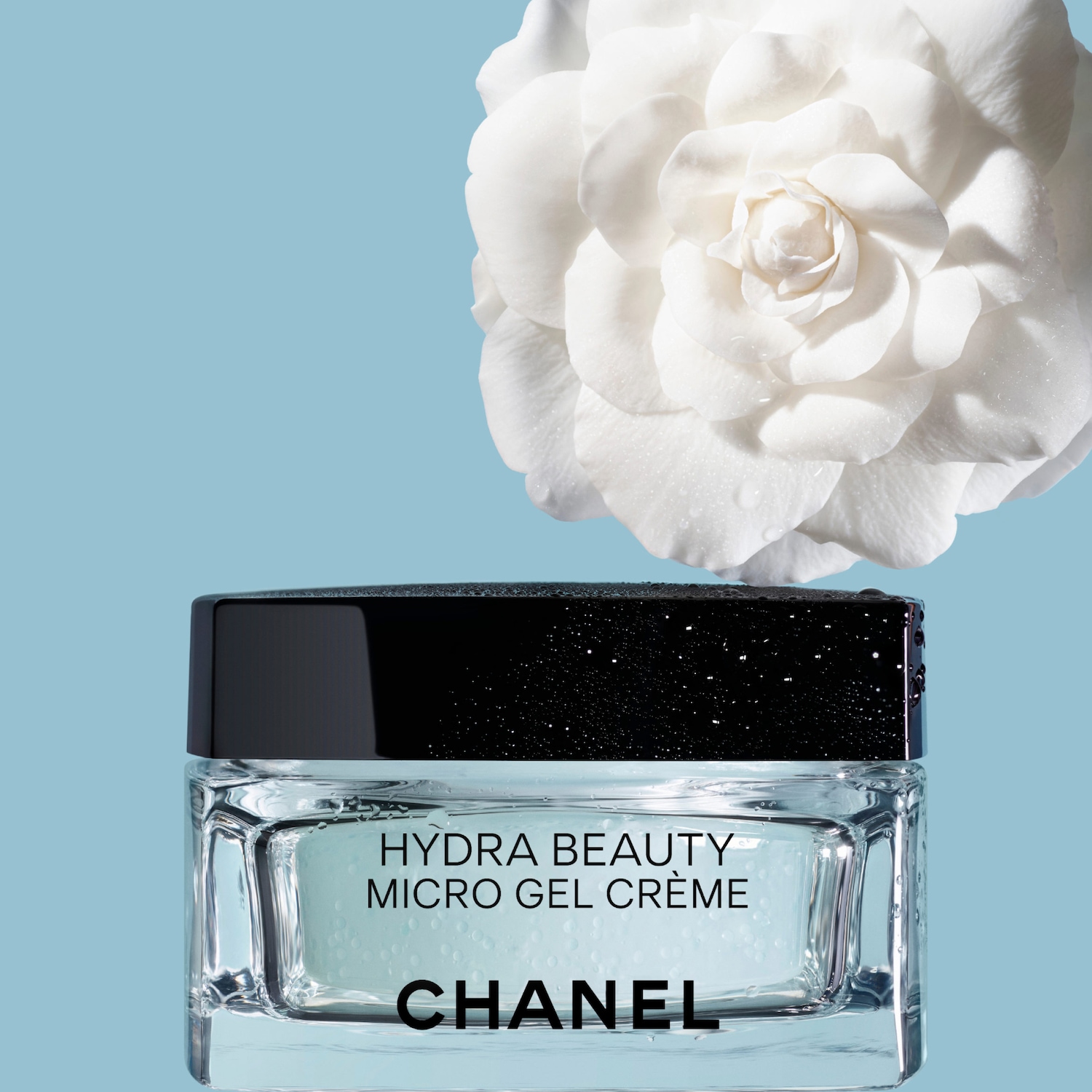 CHANEL Hydra Beauty Micro Gel Crème stiklinis kremas su juodu dangteliu ir balta kamelijos žiedu viršuje mėlyname fone.