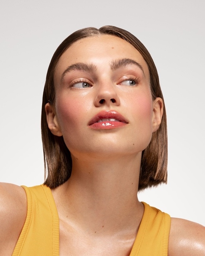 Moteris trumpais plaukais, vilkinti ryškiai geltoną palaidinę, šypsosi ir žiūri į kamerą.