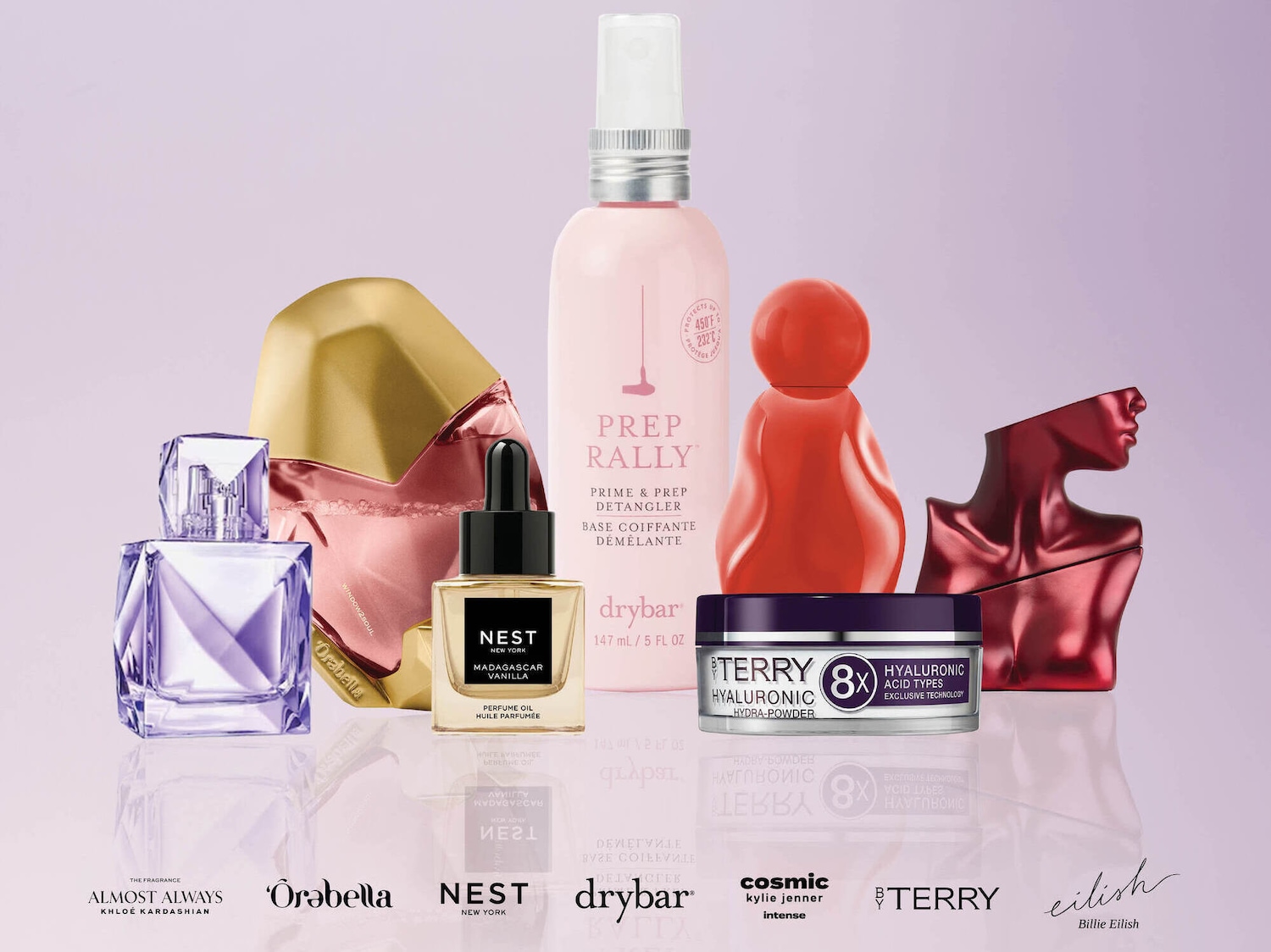 Įvairių kvepalų ir kosmetikos priemonių kolekcija, įskaitant „Almost Always Khloé Kardashian“, „Òrabella“, „Nest New York Madagascar Vanilla“ ir „Drybar Prep Rally“, išdėstyta ant šviesaus fono.