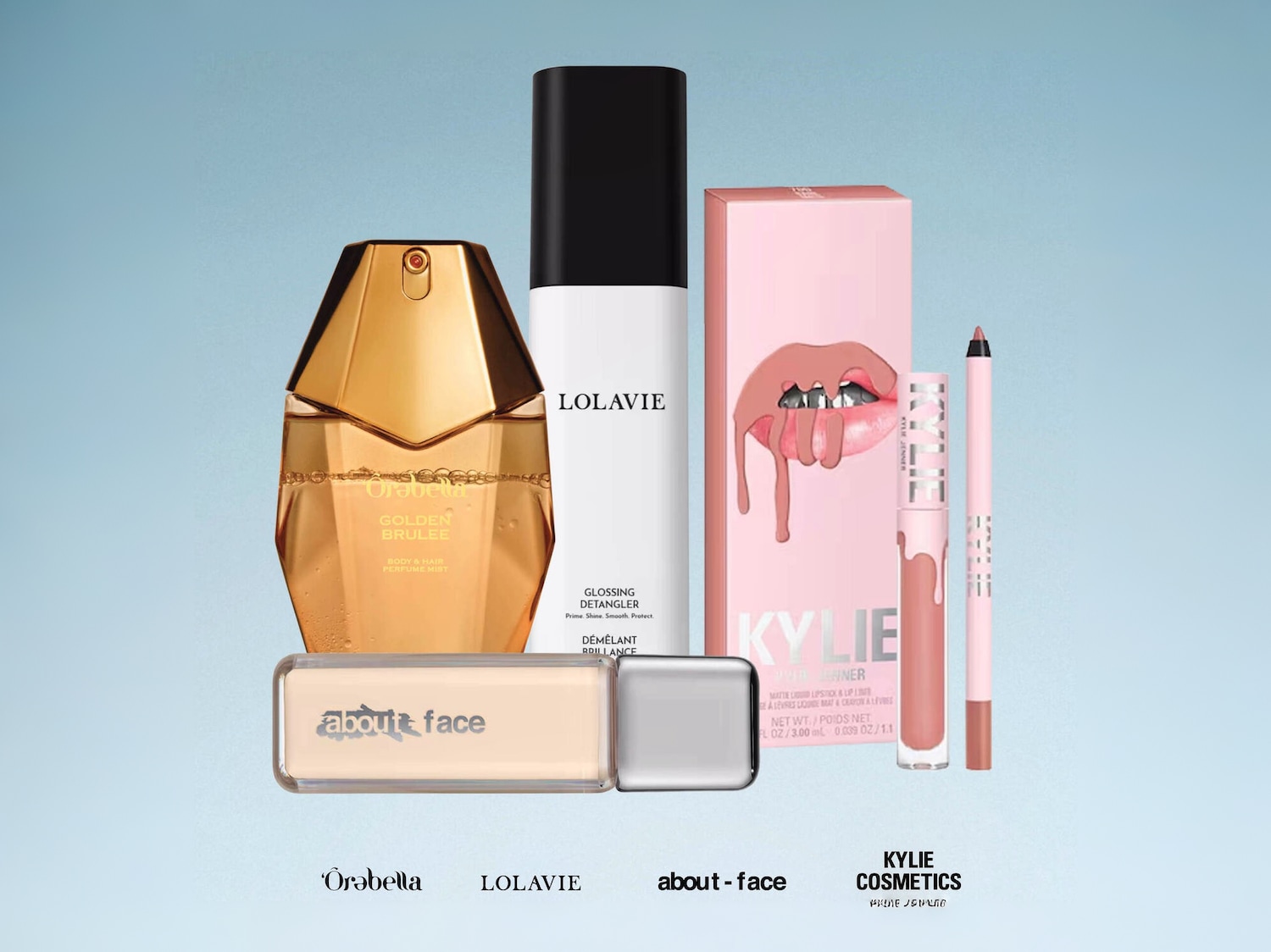 Šiame paveikslėlyje matomas „Orabella Golden Brulee“ kūno ir plaukų dulksna, „Lolavie Glossing Detangler“ ir „Kylie Cosmetics Matte Liquid Lipstick & Lip Liner“ rinkinys, išdėstyti ant šviesiai mėlyno fono.