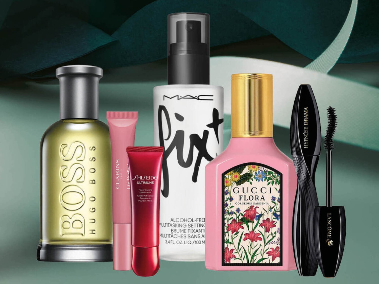 Šiame paveikslėlyje pavaizduoti įvairūs grožio produktai, įskaitant „Hugo Boss“ kvepalus, „Clarins“ lūpų balzamą, „Shiseido Ultimune“ rankų kremą, „MAC Fix+“ purškiklį, „Gucci Flora Gorgeous Gardenia“ kvepalus ir „Lancôme Hypnôse Drama“ blakstienų tušą.