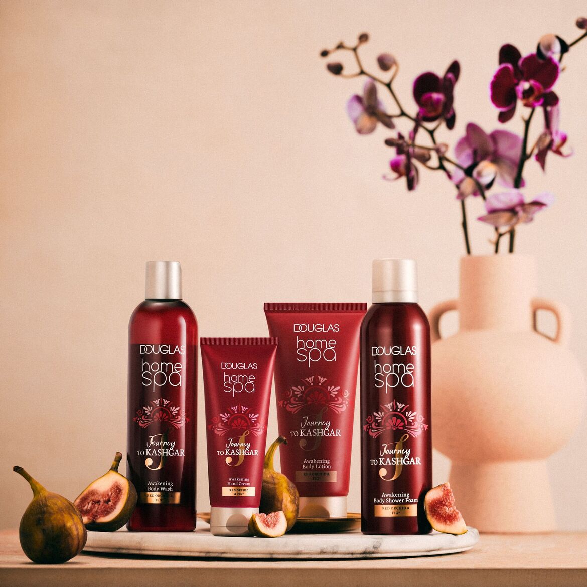 Keturių „Douglas Home Spa“ kūno priežiūros priemonių, įskaitant kūno prausiklį, rankų kremą, kūno losjoną ir kūno prausimosi putas, rinkinys su raudonosios orchidėjos ir figų aromatu, skirtas odai atgaivinti.