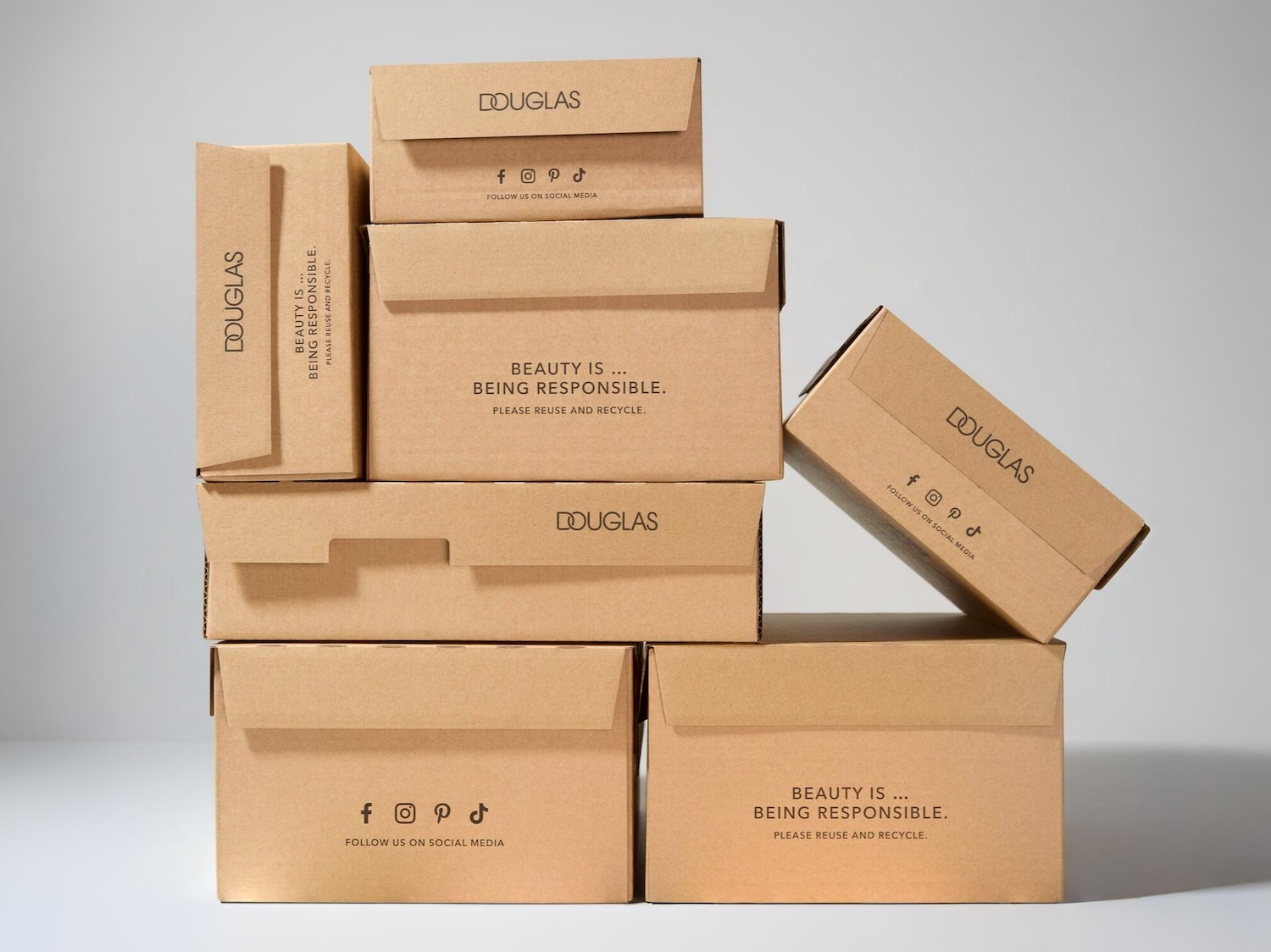 Dėžės su DOUGLAS logotipu ir reklama, vizualas skirtas prisatyti nemokamui kurjerių pristatymui.