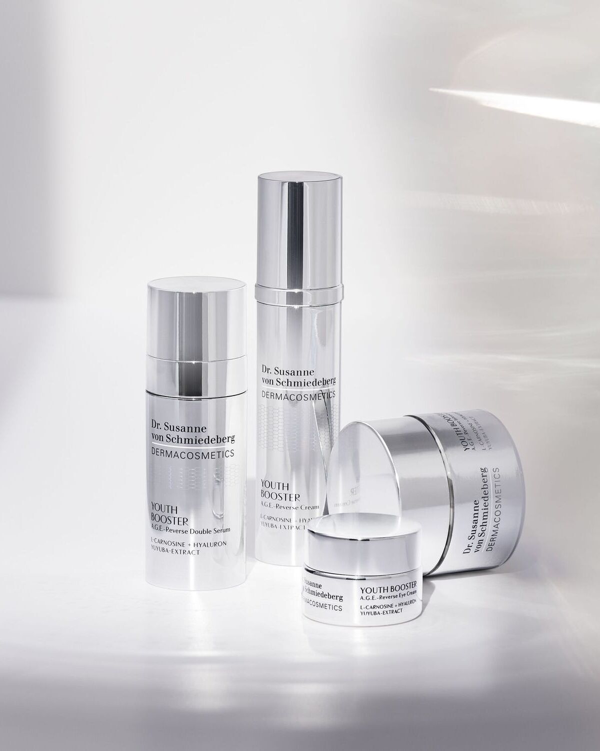 Keturi sidabriniai „Dr. Susanne von Schmiedeberg DERMACOSMETICS“ odos priežiūros produktai, įskaitant serumą, kremą ir paakių kremą, skirti jaunystei atgaivinti.